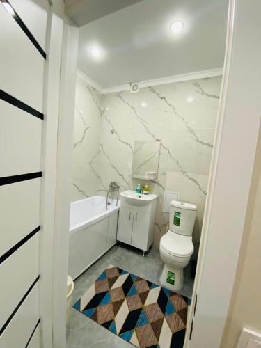 阿斯塔纳1кмн Квартира по проспекту Республика 30的白色的浴室设有卫生间和浴缸。