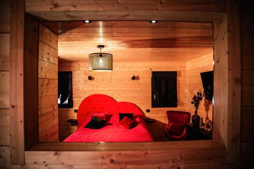 XertignyDomaine de la vôge & chalets et spa的木制客房内的一张红色床