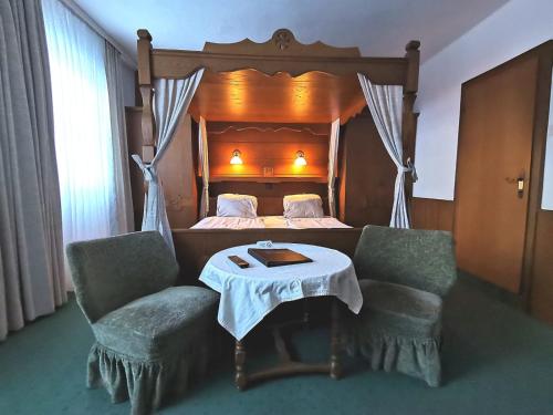 圣迈克尔隆高Hotel Gasthof Stranachwirt的一间卧室配有一张带桌子和两把椅子的床
