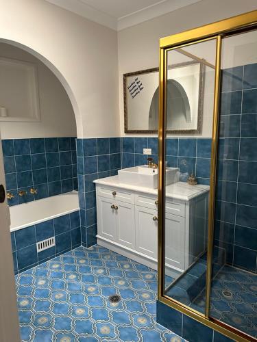 棕榈滩棕榈海滩住宿加早餐旅馆的浴室铺有蓝色瓷砖,配有水槽和淋浴。