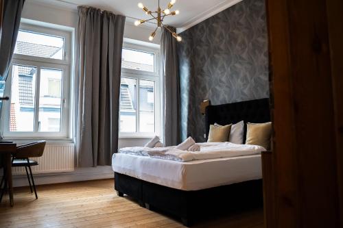 杜伊斯堡JUNIK Apartments - Deine Cityapartments in Duisburg的一间卧室设有一张床和两个窗户。