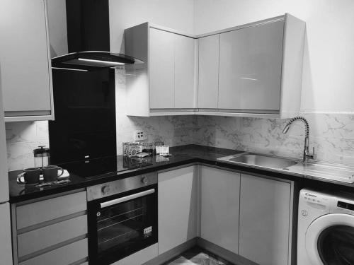 利明顿温泉High Street, 2 bed, newly refurb的厨房配有白色橱柜和洗衣机。