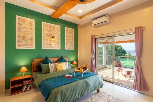 潘奇加尼Malibu Villa by Hill Staytion的一间带绿色墙壁和一张床的卧室以及一个阳台