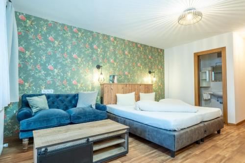 罗伊特Hotel Krone Tirol的一间卧室配有一张床和一张蓝色的沙发