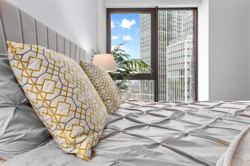 伦敦Central London New 2 bedroom flat Riverview Balcony的卧室配有带枕头的床铺和窗户。