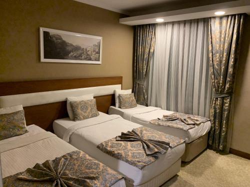BostaniçiMOONLİGHT HOTEL的酒店客房设有三张床和窗户。