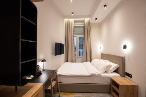 贝尔格莱德Hop Inn Rooms & Suites的一间卧室配有一张床、一张书桌和一台电视