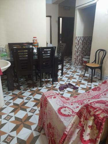 SunāmganjIsolated guest house的客厅配有桌椅,地面铺有木地板。
