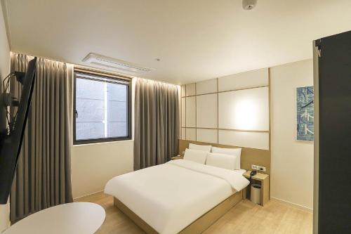 大田The Hyoosik Aank Hotel Daejeon Yooseong Hot Spring 1st Branch的卧室配有白色的床和窗户。