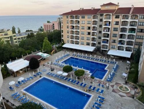金沙Apartment Golden Sands and Black Sea, Varna的一座带蓝色椅子的大型游泳池和一座建筑