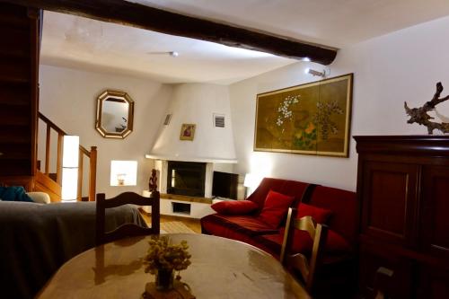 圣吉扬莱代塞尔CHARMANTE MAISON A SAINT GUILHEM LE DESERT的客厅配有桌子和红色沙发