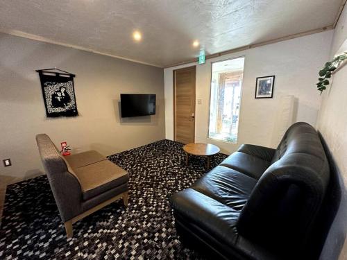白马村AOBA Hakuba self-contained home的客厅配有黑色真皮沙发和椅子