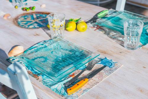 皮诺港Case Vacanze Il Sogno的一张带蓝色板子和玻璃的木桌