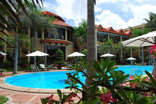 美奈天逸度假酒店的度假村前的游泳池配有遮阳伞