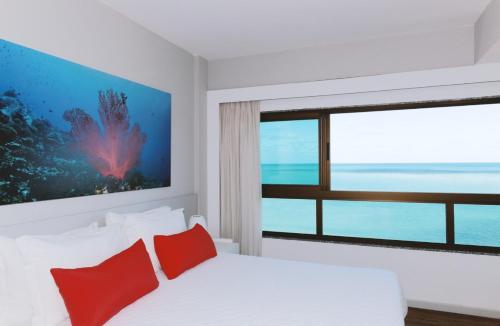 马塞约蓬豪园马塞约酒店的一间卧室配有一张带红色枕头的床和一扇窗户