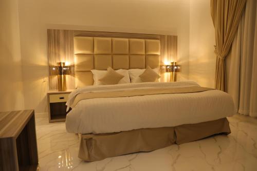 利雅德روز نجد للشقق الفندقية的一间卧室配有一张带两盏灯的大型白色床。