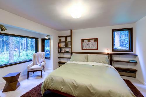 DumontMid-Century Cabin Creekside, Easy Access to i-70的一间卧室配有一张床和一把椅子,还有两个窗户