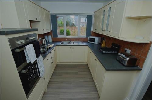 贝克斯利Charming 5 Bedroom House in Bexley的厨房配有白色橱柜和黑色台面