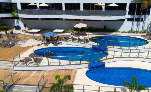 伊瓜苏福斯假日酒店的酒店游泳池设有两个游泳池、桌子和遮阳伞