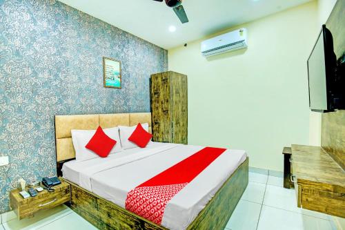 卢迪亚纳OYO Hotel Grace Villa的一间卧室配有一张带红色枕头的床和一台电视。