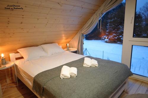 比亚沃维耶扎SzumiPuszcza - domki, sauna, jacuzzi的一间卧室配有一张床,上面有两条毛巾