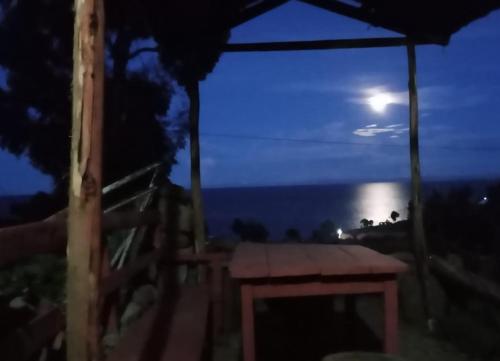 奥科苏尤BLUE SKY Amantani Lodge的夜间在雨伞下野餐桌与月亮