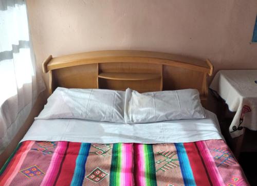 奥科苏尤BLUE SKY Amantani Lodge的一张带木制床头板和彩色毯子的床