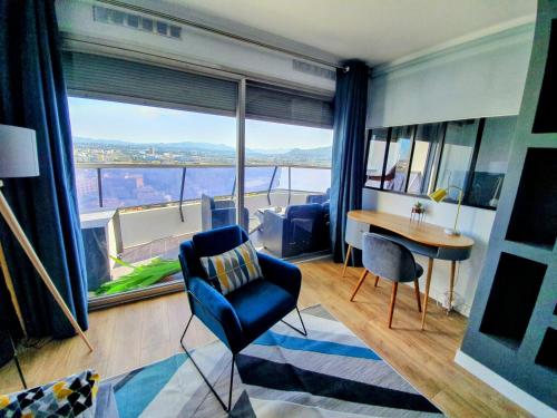 马赛Appartement T2 Prado Chanot Plage Marseille的客厅配有蓝色椅子、桌子和大窗户