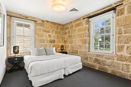 悉尼Balmain Wharf l 2 Bedroom Apartment的砖墙卧室配有一张床和两个窗户