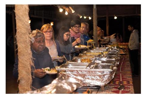 迪拜Luxury Overnight stay in Desert Safari Campsite, with dinner, adventure, entertainments, and transfers的一群人站在自助餐厅旁,一边吃食物