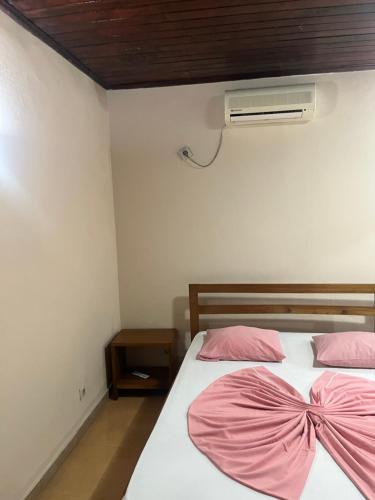 圣多美Elitineide Guest House的一间卧室配有两张床、粉红色的床单和风扇
