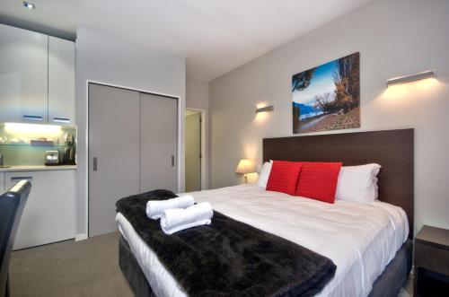皇后镇Pure Retreat Lake View的一间卧室配有一张带红色和白色枕头的大床