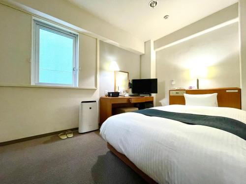 青森Aomori Green Park Hotel的一间卧室配有一张床、一张书桌和一个窗户。