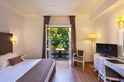 索伦托Grand Hotel Parco del Sole - All Inclusive的酒店客房配有一张床、一张书桌和一台电视。