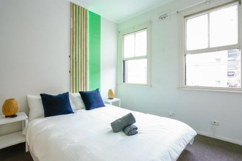 悉尼Superb 2 Bedroom House Darlinghurst 2 E-Bikes Included的卧室配有带蓝色枕头的大型白色床