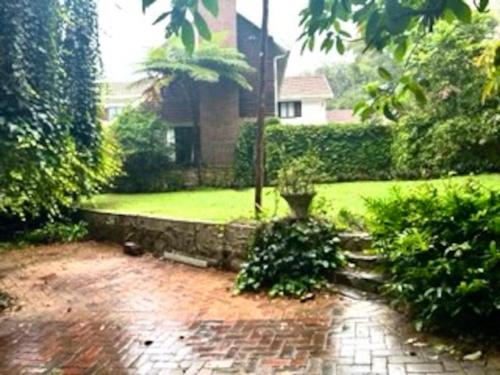 德班Sherwood Garden Cottage的房屋前有砖路的花园
