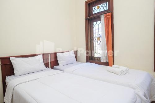 科贾扬Griya Fatima Mitra RedDoorz near UGM的带窗户的客房内的2张白色床