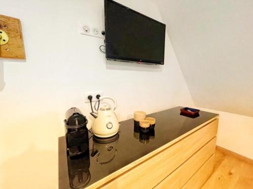 埃圭斯海姆Chambre Rose des Vents的客房设有电视和带茶壶的桌子。