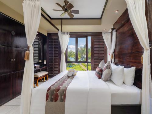 拉古洼娜湾假日酒店的一间卧室配有一张大床和吊扇