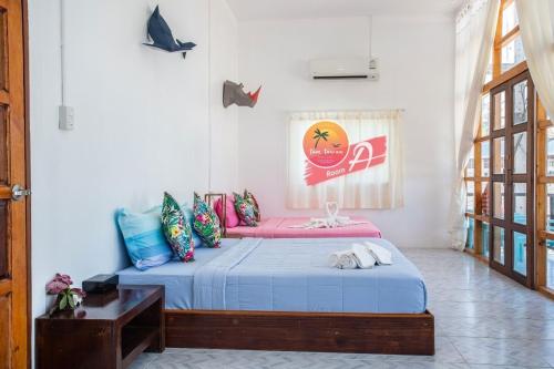 丽贝岛Tamtawan Guesthouse - ตามตะวันเกสเฮ้าส์的一间卧室配有一张带蓝色床单和粉红色沙发的床。