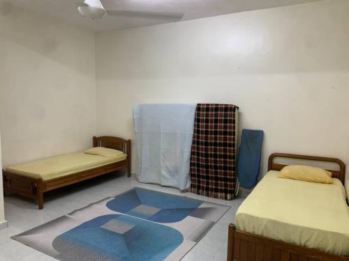 Rantau PanjangZahra Homestay的一间设有两张床的客房,地板上铺有地毯。