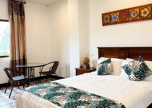 维拉港Crown Royale Hotel & Lounge的卧室配有一张床和一张桌子及椅子