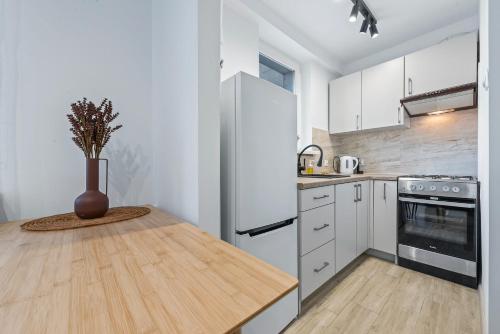 华沙RentPlanet - Apartament Syreny的厨房配有木桌和白色冰箱。