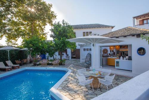 霍里顿Aeolos Hotel & Villas - Pelion的房屋旁的游泳池配有椅子和遮阳伞