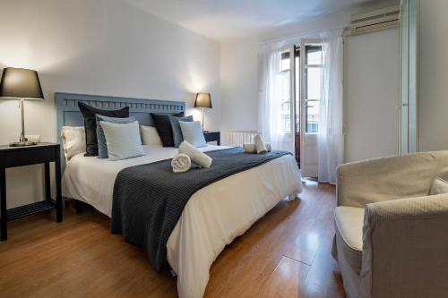 巴塞罗那人居艺术公寓的一间卧室配有一张大床和一把椅子