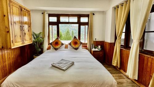 大吉岭Darjeeling Hillside Inn的卧室配有一张大白色床和窗户