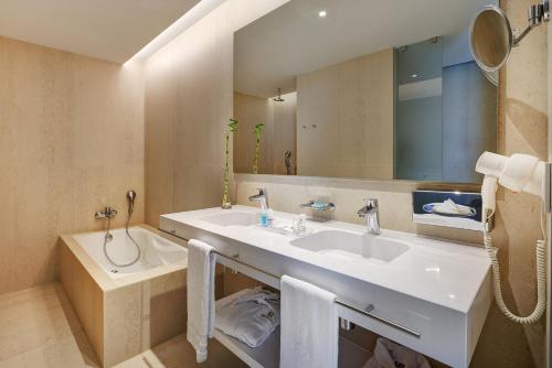 帕尔马海滩帕尔马海滩格兰时尚酒店的浴室配有盥洗盆、镜子和浴缸