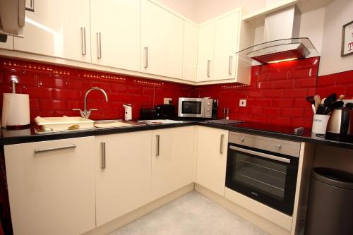 爱丁堡Hamish's Hame Edinburgh Licence No EH 69774 P的厨房配有白色橱柜和红色墙壁