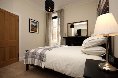 爱丁堡Hamish's Hame Edinburgh Licence No EH 69774 P的一间卧室配有一张带灯和镜子的床
