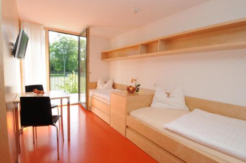 多恩比恩Olympiazentrum Vorarlberg的客房设有两张床、一张桌子和一张桌子。